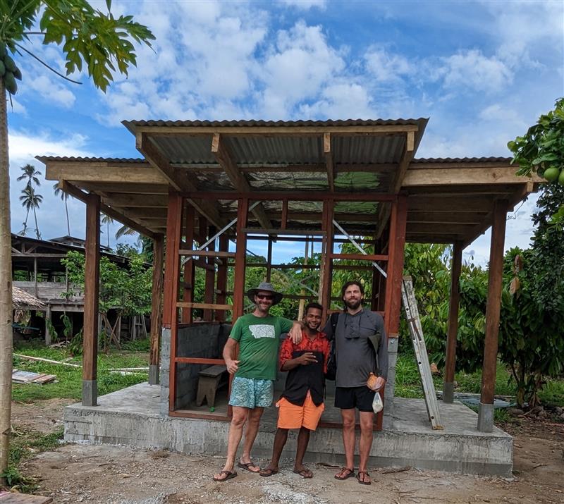 Three people standing beside a Powa Haus under construction